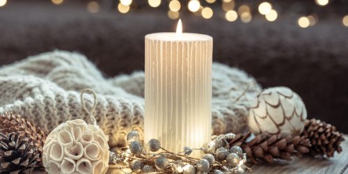 Winter festive background with burning candle and home decor details on blurred background with bokeh.